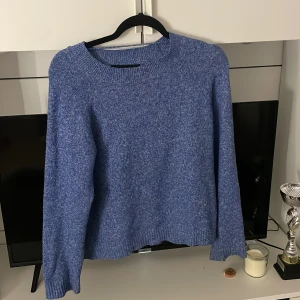 Blå stickad tröja från Vero Moda - Mysig blå stickad tröja från Vero Moda i storlek S. Tröjan har rund hals, ribbade muddar och långärmad passform. Perfekt för att hålla dig varm och snygg under kyliga dagar. Enkel att matcha med jeans eller kjol för en chill look.