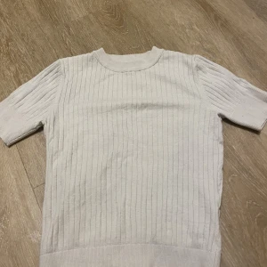 Vit ribbad tröja från Object - Säljer en vit ribbad tröja från Object i storlek S. Tröjan har korta ärmar, rund hals och är tillverkad i mjukt stickat material. Perfekt för dig som gillar enkel och clean stil med lite struktur i tyget.