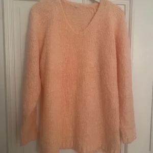 Ljusrosa stickad tröja med v-ringning - Supermjuk och mysig ljusrosa stickad tröja med v-ringad hals och långa ärmar. Perfekt för kyliga dagar och enkel att styla med jeans eller kjol. Oversized känsla för extra komfort.