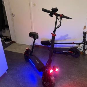 Elscooter med LCD-display och sadel - Kraftfull elscooter från Vsett med stor LCD-display, nyckelstart och bekväm sadel. Utrustad med LED-belysning, robusta däck och stötdämpning. Snygg design med blå sidobelysning. Mycket gott skick, inga synliga defekter eller slitage. Snabbheten är 55 km/s. Den kommer även med 2 st nycklar.                             Srad: Linköping 