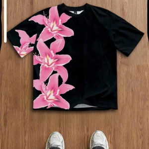 Svart t-shirt med stora rosa blommor - Svart t-shirt med oversized passform och stora rosa blommor tryckta längs ena sidan och ärmen. T-shirten har rund hals och korta ärmar. Perfekt för dig som vill sticka ut med en färgstark och unik look.