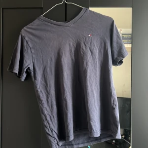 Mörkblå t-shirt från Tommy Hilfiger - Snygg mörkblå t-shirt från Tommy Hilfiger med v-ringning och liten broderad logga på bröstet. Jag e tjej och tycker den sitter fint på mig! 