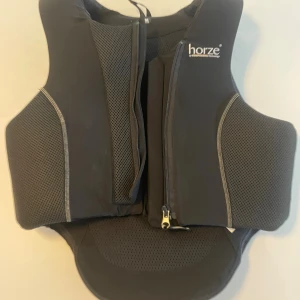 Skyddsväst Horze M Slim - Säljer en svart skyddsväst från Horze by KOMPERDELL technology. Västen är CE-godkänd, Level 3 och otroligt skön att ha på sig! Endast använd en gång. Slim fit M och 360° skydd. Ordinarie pris 2390kr. Skriv för mer information!