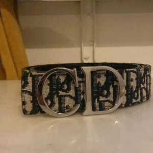 Christian Dior bälte - Säljer ett snyggt bälte från Christian Dior med ikoniskt CD-spänne i silverfärgad metall. Bältet har ett svart och vitt mönster med Dior-logga och är tillverkat i skinn och textil. Pris kan diskuteras vid snabb affär!