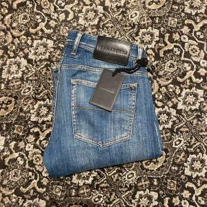 Ljusblå jeans från Tramarossa, W32 - Snygga blå jeans från Tramarossa i klassisk tvätt och broderad detalj vid gylfen. Modellen är slim, fem fickor och logotyp på bakfickan. Jeansen är tillverkade i mjukt denimtyg med snygga kontrastsömmar. Skick 9/10 tag finns kvar. Ytterbenlängd 102,5 cm. Innerbenlängd 81,5 cm. Midja 42,5 cm. (Måttavvikelser +-1cm)