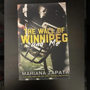 The Wall of Winnipeg and Me - En populär roman av Mariana Zapata, perfekt för dig som gillar sport och starka karaktärer. Omslaget visar en amerikansk fotbollshjälm och en gräsplan, vilket ger vibbar av sport och relationer. Passar unga vuxna som söker en engagerande berättelse.