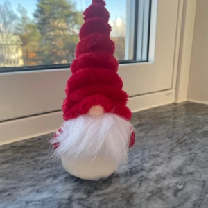 Röd tomte i plysch - En väldigt fin tomte med spiralfomad röd tomteluva i mjuk plysch, perfekt för julens alla tillfällen. Tomten är lång och konformad med tydlig struktur och passar utmärkt till dekoration.