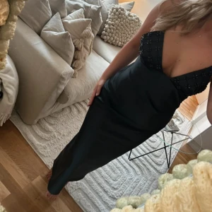 Svart långklänning  - Svart långklänning i satin med smala band och små pärlor upptill. Jättefin till bal eller sittning och går nästan ner till marken på mig som är 167 cm. Dragkedja i bak och bra i storlek🩷