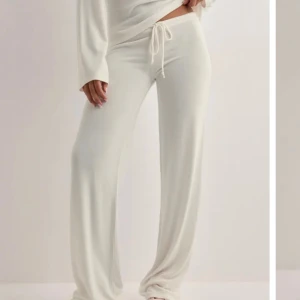 Vita mjukisbyxor med snörning från Nelly - Supermjuka vita mjukisbyxor från Nelly i storlek XXS. Byxorna har låg midja, vida ben och snörning i midjan för perfekt passform. Perfekta för chill dagar hemma eller när du vill vara extra bekväm. De är helt nya, och de är upp sydda så de passar dem som är runt 160-165.
