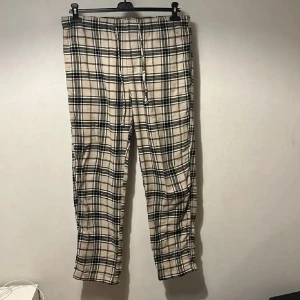 Pyjamasbyxor  - Snygga rutiga byxor från H&M i beige och svart med dragsko i midjan. Tillverkade i 100% bomull för en skön och avslappnad känsla. Perfekta för en chill och trendig look, passar till sneakers eller boots.