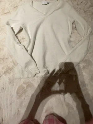 Vit stickad tröja från VILA - Säljer en vit stickad tröja från VILA i storlek S. Tröjan har v-ringad hals, långa ärmar och ribbade muddar vid ärmslut och nederkant. Perfekt för att hålla sig varm under kyliga dagar och passar till många olika stilar.