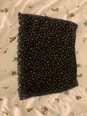 Svart blommig minikjol från hm - Svart minikjol från H&M Divided med små blommor. Kjolen har volangkant nertill. Kjolen är nästan aldrig använd. Och i storlek s.