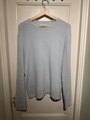 Ljusblå stickad tröja Jack & Jones - En stilren ljusblå stickad tröja från Jack & Jones i storlek S.(passar även M!) Tröjan har rund halsringning och lång ärm, perfekt för lager-på-lager. Mjuk och skön känsla med enkel design som funkar till många outfits.tröjan är i mycket bra skick förutom ett litet hål vid höger armhåla som man då ser på fjärde bilden!