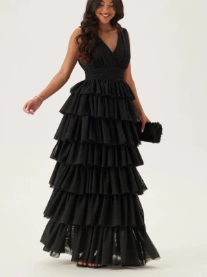 Svart volangklänning med v-ringning - Supersnygg långklänning i svart med flera lager volanger och djup v-ringning. Klänningen är ärmlös och har markerad midja med bredt band. Perfekt för bal eller festliga tillfällen. Materialet känns lätt och ger ett lyxigt intryck.