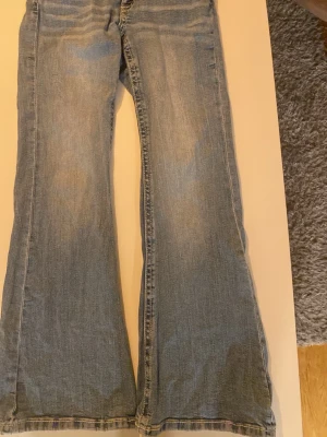 Blå bootcut jeans Gina Tricot 152 - Säljer ett par ljusblå bootcut jeans från Gina Tricot i storlek 152. Klassisk femficksmodell med utsvängda ben och normal passform. Jeansen är tillverkade i mjukt denimtyg och har en snygg tvättad look. Har nästan aldrig andvänt så de har inga tecken på andvändning. 