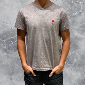 Ami Paris T-shirt Grå - •Ami-Paris t-shirt grå. Skick: 9/10, mycket fint skick & inga defekter! Storlek: S. Modell: 173 cm, 63 kg. Sitter bra på modell! Nypris: 1 400 kr.  Authentic: ✅, qr kod finns i plagget! Hör av dig vid frågor eller funderingar.