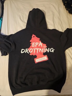 Svart hoodie med rosa tryck  - Säljer min svarta hoodie där det står epa drottning litet fram och stort baktill. Säljer då den inte kommer till användning längre. Syns att den är använd men inget man tänker på så mycket. Nypris 500kr. Pris kan diskuteras!