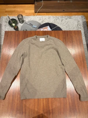 Beige stickad tröja Samsøe Samsøe - Säljer en beige stickad tröja från Samsøe Samsøe med snygga bruna mockadetaljer på armbågarna. Tröjan har rund halsringning, ribbade muddar och lång ärm. Perfekt för dig som gillar klassisk och stilren look.