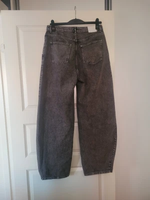 Grå barrel jeans från Gestuz - Säljer ett par grå barrel jeans från Gestuz med hög midja och riktigt breda ben. Jeansen har en cool tvättad look, klassiska bakfickor och är tillverkade i jeansmaterial. Perfekta för dig som gillar loose fit och statement-plagg.