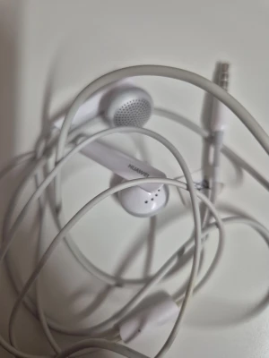 Huawei kabelanslutna hörlurar - Vita Huawei hörlurar med kabel och 3,5 mm kontakt. Klassisk design med inbyggd mikrofon. Hä