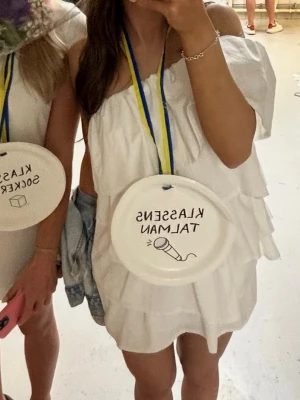 Student klänning  - Säljer en superfin vit kortklänning med offshoulder och volangdetaljer. Klänningen har en luftig passform och är perfekt för student eller sommarens alla tillfällen. Köpt från Anielle för 1400kr, endast använd 1 gång. Är i Strolek XS petite. Är själv 163 lång. Den är i bra skick! Kan diskutera priset! 🥰