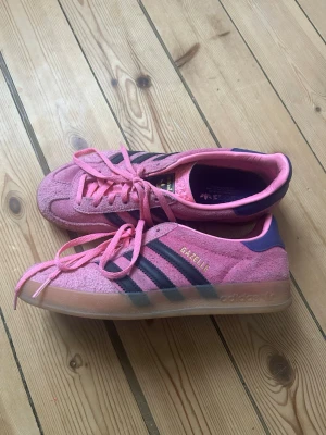 Adidas Gazelle rosa mockasneakers - Säljer ett par Adidas Gazelle sneakers i rosa mocka med lila detaljer och klassiska tre ränder på sidan. Använda fåtal gånger då de inte kommer till användning.