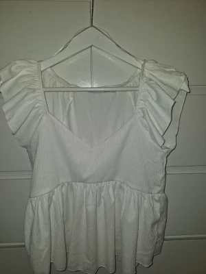 Vit volangblus från 157, stl M - Supersöt vit blus från 157 med volangärmar och v-ringning. I storlek M. I nyskick då den inte använts någon gång. Köpt sommaren 2025 för ca 50 kr. Använd gärna köp nu funktionen eller kom privat💗