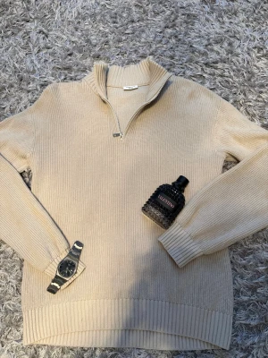 Beige stickad half zip-tröja Kappahl - Snygg beige stickad tröja från Kappahl med half zip-dragkedja och hög krage. Tröjan har ribbade muddar och är långärmad. 