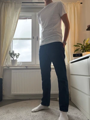 Mörkblå raka jeans - Säljer ett par mörkblå jeans med rak passform. Klassisk femficksmodell och normal midja. Jeansen är tillverkade i ett tåligt denimtyg och har en enkel, stilren look utan slitningar eller dekorationer.