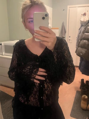 Svart spets blus vintage med långa ärmar  - En svart Spetsblus med långa ärmar och volanger. Storlek L men passar xs/s/m bra med. Köpt vintage. Märket verkar vara white stag? Blusen har knappar framtill.