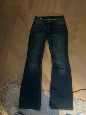 Mörkblå bootcut jeans - Säljer ett par mörkblå jeans med bootcut passform. Klassisk femficksmodell med snygga slitningar och kontrastsömmar. Jeansen har normal midja och är tillverkade i slitstarkt denimtyg. Perfekta till sneakers eller boots.W24,Längd34