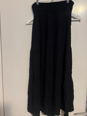 Lång svart volang kjol - Jag säljer en lång volangkjol, jag är 174cm lång och går nästan ända ner till marken, beroende på hur man har den. Jag använde den som lågmidjad. Använd få gånger och där med i väldigt bra skick.