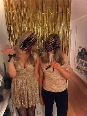 Guldklänning  - Supersnygg kort glittrig klänning i guld från Meet Me There. V-ringning och markerad midja. I nycksick, använd 1 gång. Storlek XXS-XS men passar även S