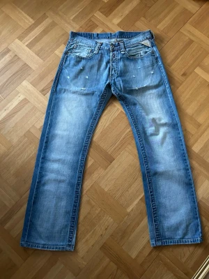 Ljusblå replay jeans  - Säljer ett par ljusblå jeans från Replay med snygga slitningar och broderade detaljer vid fickorna åt min brorsa. Klassisk femficksmodell med raka ben och normal passform. Jeansen har Replay-lapp bak i midjan och coola slitna effekter framtill. Skriv vid frågor! 