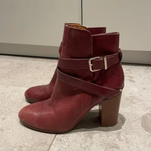 Trendiga röda stövletter med spännen – statement shoes! - Säljer ett par supersnygga röda stövletter med dekorativa spännen. Perfekta för dig som vill lyfta en enkel outfit och sticka ut med stil. Passar lika bra till jeans, klänning eller kjol – året runt