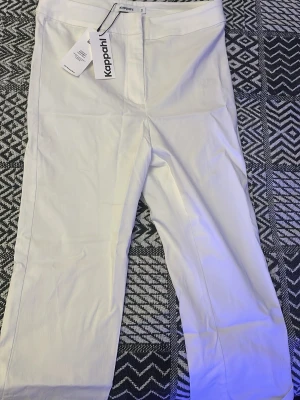 Vita raka capri från Kappahl - Snygga vita byxor från Kappahl med rak passform och klassisk midja. Tillverkade i ett mjukt bomullsmaterial som känns bekvämt hela dagen. Perfekta att styla med en enkel t-shirt eller en skjorta för en clean look.