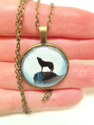 Halsband med varg hänge - Bilderna visar ett halsband med ett runt hänge som har motiv av en ylande varg mot en måne. 52 cm lång kedja