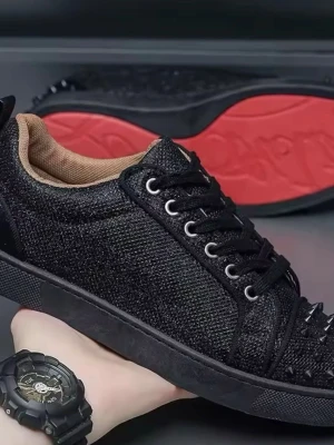 Loubs  - Säljer ett par svarta sneakers med glittrig textil och skinnpaneler. Skorna har snörning, rund tå och är dekorerade med svarta nitar på tån. Insidan är beige och yttersulan är röd med mönster. Perfekt för dig som vill sticka ut med din stil.