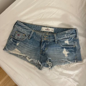 Hollister lågmidjade jeansshorts  - Så snygga lågmidjade jeansshorts från Hollister! Storlek W25. Midjemåttet tvärs över är 36cm. OBS de små vita prickarna verkar vara vita färgfläckar men syns endast på nära håll, det ser mest ut som slitningar💗💗