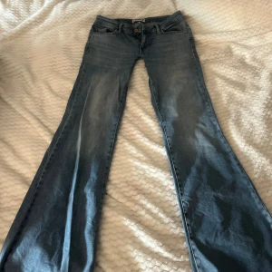 Bootcut jeans från ONLY i ljusblå denim - Snygga bootcut jeans från ONLY i ljusblå denim med klassisk femficksdesign och knappstängning. Lågidja och utsvängda! 36cm rakt över midjan. 87cm i innerbenslängd! 