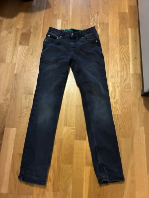 Svarta Levi's jeans straight fit - Säljer ett par svarta Levi's jeans i rak modell. Klassisk femficksdesign med knapp och dragkedja fram. Jeansen är tillverkade i en mjuk bomullsblandning med lite stretch för extra komfort. Passar perfekt till dig som gillar en clean och enkel look.