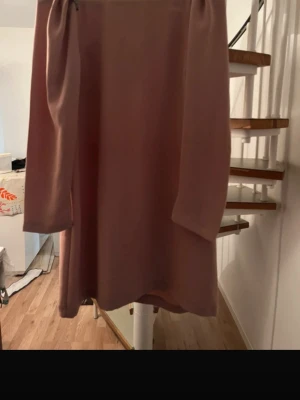 Blush Pink Long Sleeve Shift Dress - Elegant blush pink dress with a clean, minimal silhouette. Features long sleeves with subtle puffed shoulders and a straight/shift fit that falls just above the knee (depending on height). The dress has a concealed zipper at the back and a structured yet soft look, making it perfect for both formal occasions and everyday elegance. ✔ Classic & timeless ✔ Comfortable fit ✔ Easy to dress up or down Condition: Very good Size: EU 42 / US 12 Color: Blush pink / dusty rose 