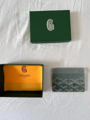 G-plånbok - Snygg och stilren i grön med deras ikoniska mönster. Plånboken har flera kortfack och är tillverkad i skinn med tryckt logga framtill. Perfekt för dig som vill ha något exklusivt och smidigt i fickan.  