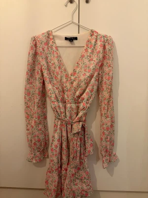 Amisu - Långärmad wrapklänning med blommönster, tunnare i armarna och slutar ovanför knäet. 