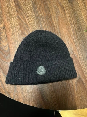 Moncler Beanie ”black label” - Säljer nu denna Moncler mössan ”black label” för en dunder STEAL, nypriset på denna låg på 3300 kronor, användt en del men har tagit bra hand om den, inga tecken på skador. Söker en snabb och smidig affär. 