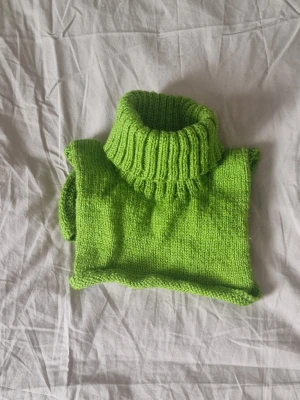 Grön stickad polokrage - En grön stickad polokrage. Perfekt att bära under jackan för extra värme. Ribbstickad hög krage. Enkel att dra över huvudet. Den är såpass flexibel att jag som vuxen får den över huvudet. Otöjd är öppningen ca 8 cm.