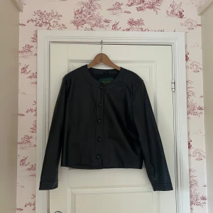 Svart skinnjacka med knappar - Det står att den är st XL men tror att det är en kroppad model. Jag som brukar ha M/L i jackor tycker den passar bättre då den sitter som en vanlig jacka🩷 jag har tagit ut vadderingen i axlarna så de är två hål inuti jackan där av sänker jag briset, men de går att sy igen 