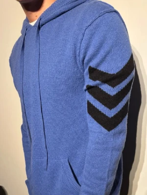 Blå kashmir hoodie Zadig Voltaire - Säljer en väldigt snygg blå kashmir hoodie med svarta chevron-detaljer från Zadig Voltaire. Den har huva med dragsko och magficka. Skriv om du vill se fler bilder eller försök komma med något pris förslag.