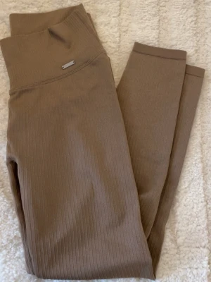 Ribbade leggings från Aim'n i beige - Använda 3-4ggr. Inga defekter. Snygga ribbade leggings från Aim'n i en beige färg. De har hög midja och är tillverkade i mjukt, stretchigt material med 95% nylon och 5% elastan. Perfekta för träning eller chill, med en slim passform som sitter skönt och följer kroppen.