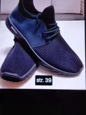 Svarta sneakers strl 39 - Säljer ett par svarta sneakers i storlek 39. Skorna har en stickad ovandel och snörning framtill. Sulan är platt och mönstrad för extra grepp. Perfekta för dig som gillar en enkel och sportig stil.
